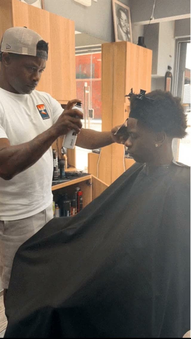 A barber finishing a client's cut at Fresh Cutz Barbers