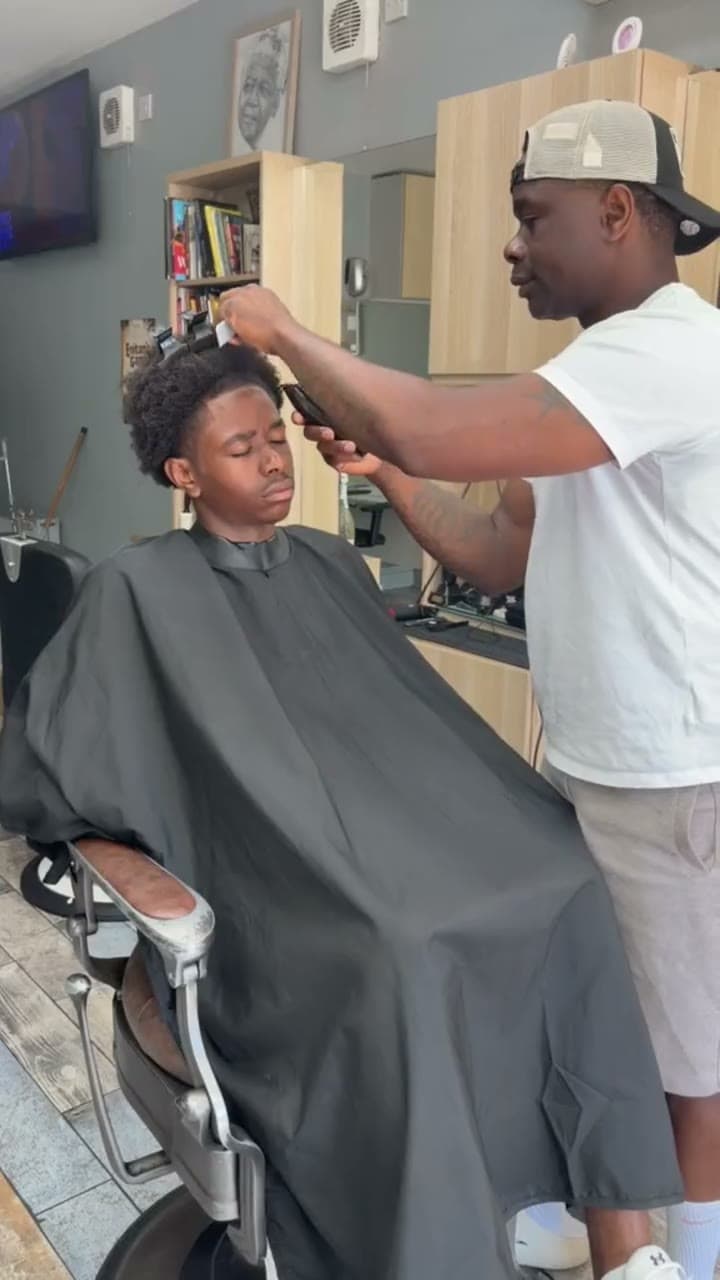 A barber running clippers along a client's hairline at Fresh Cutz Barbers